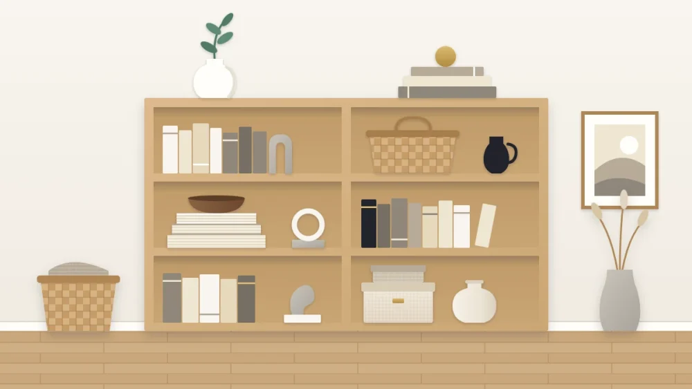 A light oak bookcase styled in neutrals with cream and gray books, a white vase, a woven basket, a wooden bowl, a near-black jug and one green stem